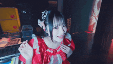 a girl in a red dress with a tiara on her head giving a thumbs up