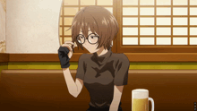 a girl with glasses is sitting at a table with a glass of beer in front of her