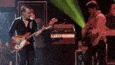 a man playing a guitar on a stage with a box with the letter s on it