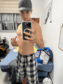 a shirtless boy taking a picture of himself in a bedroom