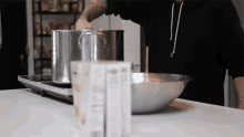 a man in a black hoodie is pouring milk into a bowl