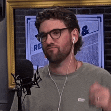 a man wearing glasses and earbuds is standing in front of a microphone