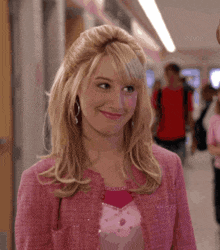 a blonde woman wearing a pink jacket and pink shirt smiles