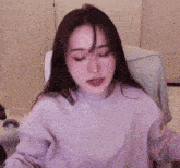 a woman is sitting in a chair wearing headphones and a purple sweatshirt .