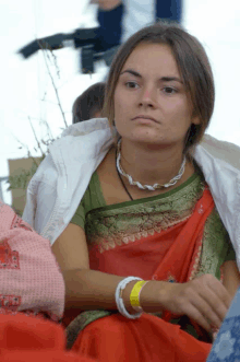 a woman wearing a red and green sari has a yellow wristband on her wrist that says ' i love you '