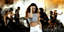 a woman in a crop top is dancing in front of a group of dancers and the word alismehc is on the bottom