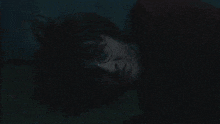 a close up of a person holding a pumpkin in front of their face in a dark room .