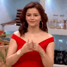 a woman wearing a red off the shoulder dress is clapping her hands