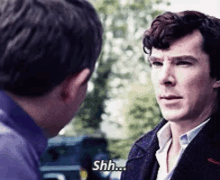 a man in a suit is talking to another man and says shh .