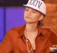 a woman wearing a red shirt and a white hat is sitting down .