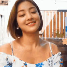 a close up of a woman wearing a floral off the shoulder top .
