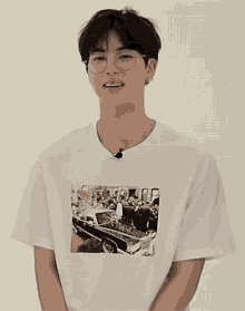 a young man wearing glasses and a white t-shirt has a picture of a car on it .