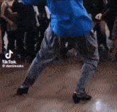 a man in a blue shirt is dancing on a dance floor in front of a crowd .