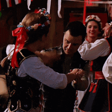 a woman wearing a black vest and a red necklace is dancing with a man