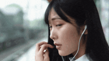 a woman wearing ear buds looks down at something