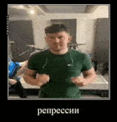 a man in a green shirt is standing in front of a drum set and making a funny face .