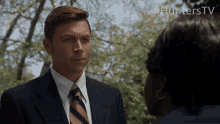 a man in a suit and tie talks to a woman with #hunterstv written in the corner