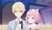 a boy and a girl are standing next to each other and the girl is holding a cell phone .