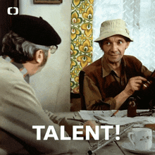 two men are sitting at a table with the word talent written on the bottom