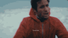 a man in a red jacket with the word tues geniale on the front