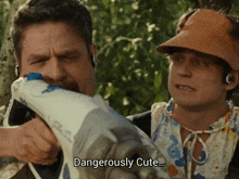 a man is holding a gun next to another man who says dangerously cute