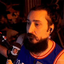 a man with a beard wearing ear buds and a that 's what she said sticker on his shirt
