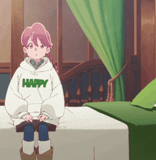 a girl is sitting on a bed wearing a happy sweatshirt