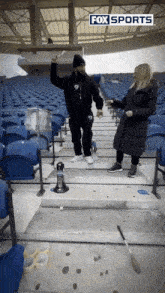 a man and a woman are standing in a stadium with fox sports written on the top