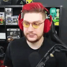 a man with red hair and glasses is wearing headphones and a microphone .