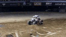 a monster truck is driving on a dirt track in front of a walmart and lucas oil banner