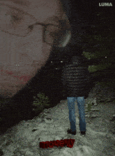 a man in a black jacket stands in the snow with a luma logo in the background