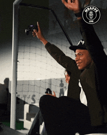a man with his arms in the air is wearing a mbappe live logo