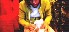 a man wearing a yellow jacket is holding a white object