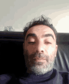 a man with a beard is sitting on a chair with his eyes closed