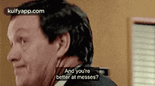 a man in a suit and tie is talking to another man in a room .