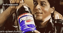 a man is holding a bottle of pepsi and drinking it .
