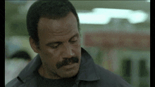 a man with a mustache is wearing a grey jacket