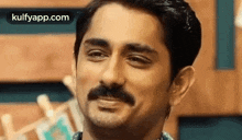 a man with a mustache is making a funny face .