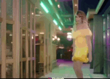 a woman in a yellow off the shoulder dress is walking down a hallway