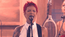 a woman with red hair singing into a microphone with her eyes closed