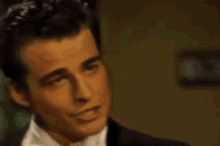 a man in a tuxedo and bow tie is looking at the camera