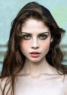 a close up of a woman 's face with blue eyes and brown hair
