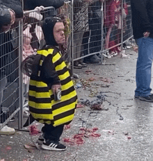 a little boy in a bee costume holds a bottle