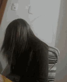 a woman 's head is visible in front of a wall with a light switch on it
