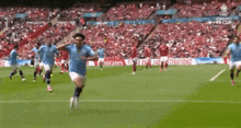 a group of soccer players are running on a field with an emirates advertisement in the background