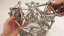 a person is holding a metal structure with balls and sticks in their hands