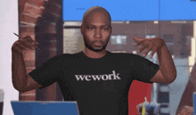 a man wearing a wework t-shirt holds his hands up