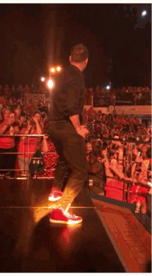a man stands on a stage in front of a crowd holding a microphone