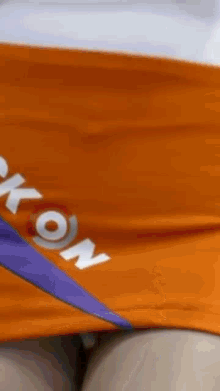 a woman is wearing an orange skirt with a purple stripe on the side .