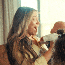 a woman laughs while holding a baby 's hand